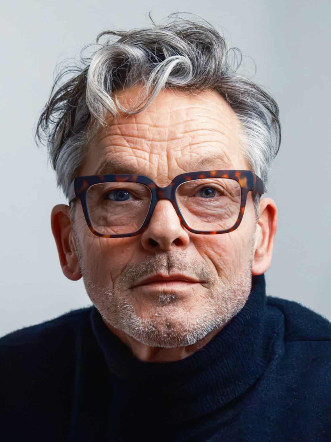 Portrait professionnel en couleur. portrait photographié par une femme. Il s'agit d'un gros plan d'un homme de 60 ans, avec des rides et portant des lunettes et un bleu.