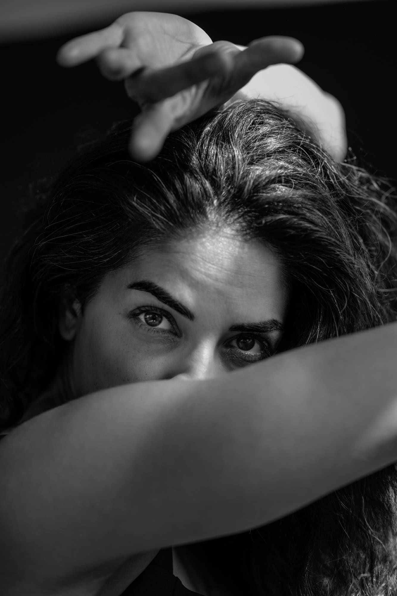 Portrait artistique créatif noir et blanc. Femme rayant posture flamenco avec bras devant visage et main opposée au-dessu de la tête. Femme regardant droit dans le yeux objectif, regard défiant.