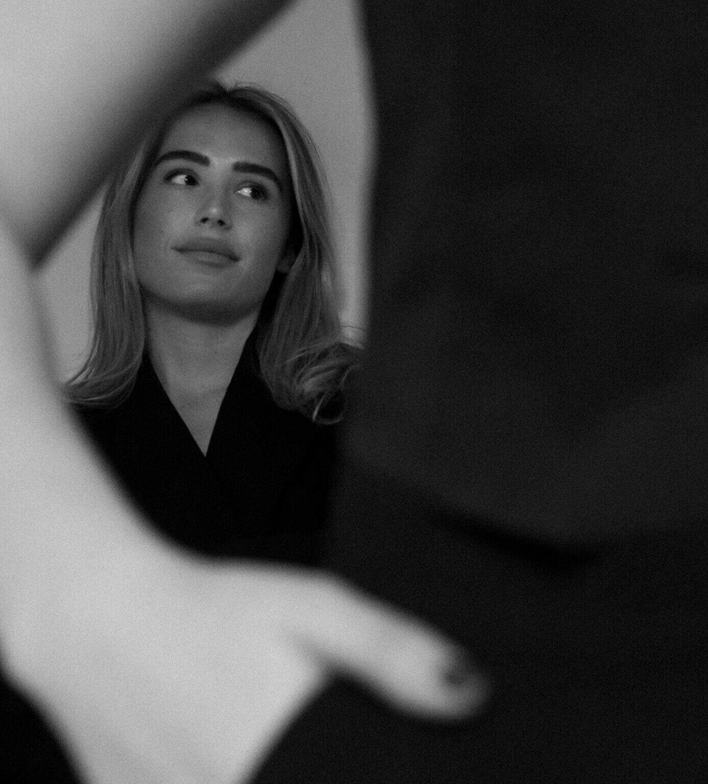 Portrait artistique noir et balnc. photographié par une femme. Jeune femme apparaît dans le cadre du bras d'une autre femme qui a sa main dans sa poche. Photographie avec du grain