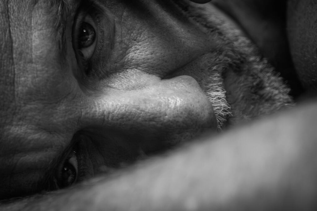 nu artistique masculin en noir et blanc, portrait intimiste photographié par une femme. Gros plan sur visage homme couché sur le sol